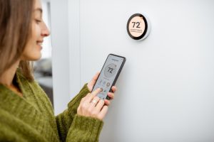 person-adjusting-thermostat-with-an-app-on-their-phone