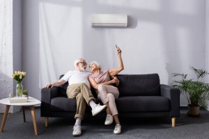 a-happy-couple-sitting-in-front-of-a-ductless-air-handler